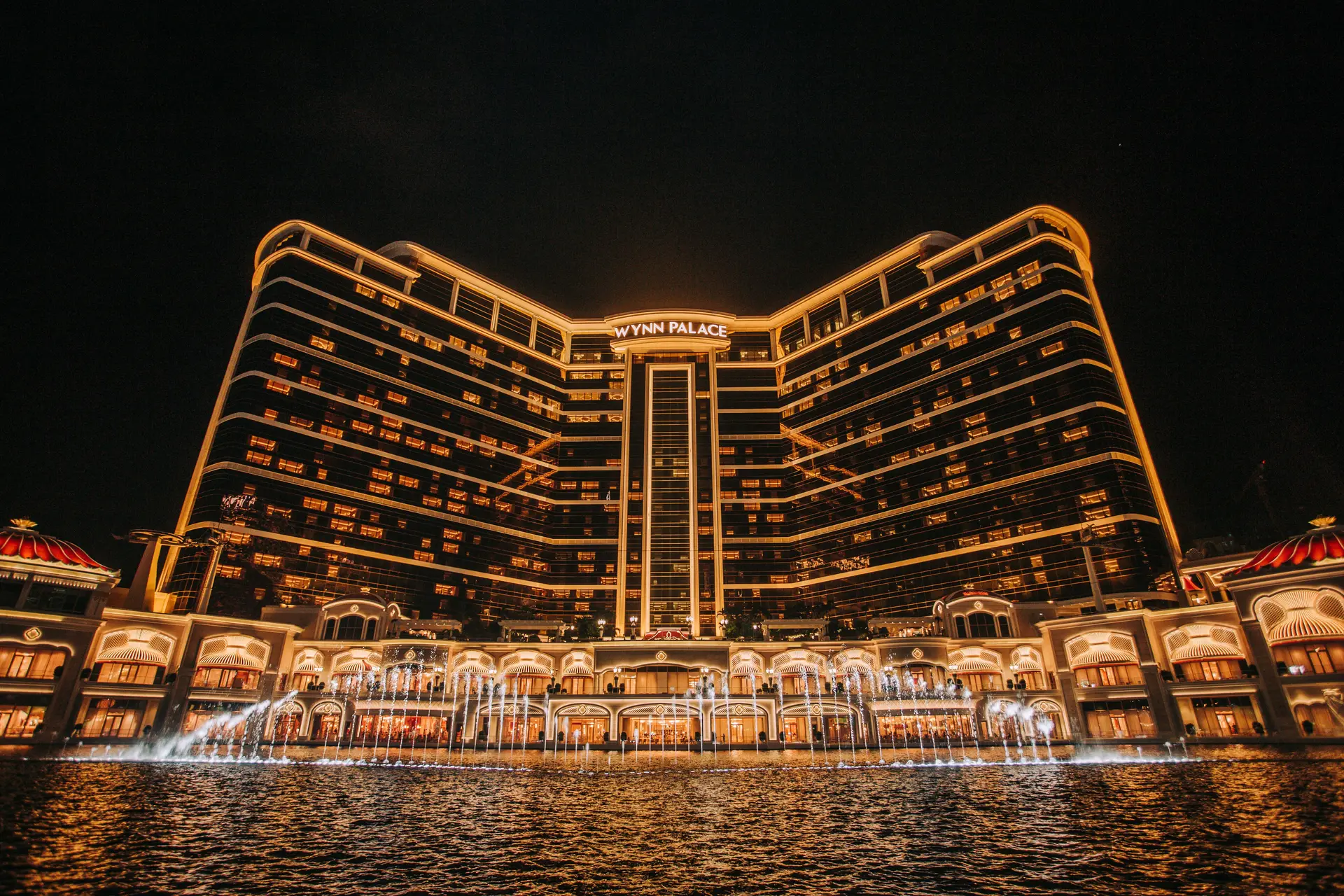 Palatial casino resort courtyard with illuminated waters and upscale architectural promenade